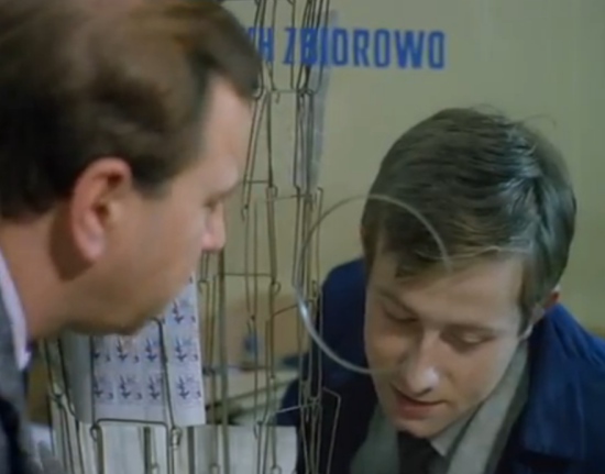 El mismo actor que representaba el papel de Tomek atiende a Jerzy. Lo hace en un mostrador de una Oficina de Correos y comunicándose con el cliente a través del 